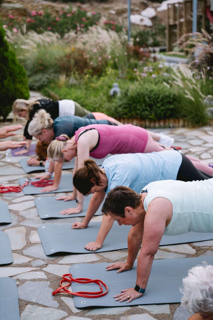 Exercises to avoid during menopause. 5 women on yoga mats doing press-ups.