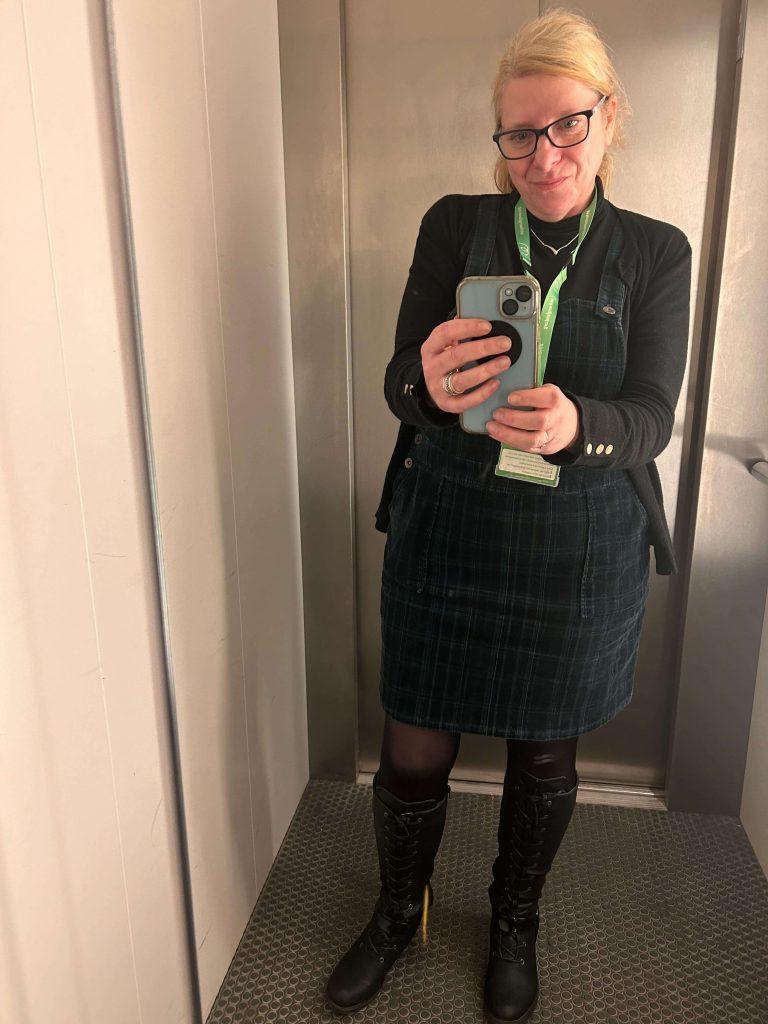 Weight loss success stories: Rebecca taking a full length selfie in a mirror, smiling in a pair of knee high boots and a checkered dress after her weight loss.