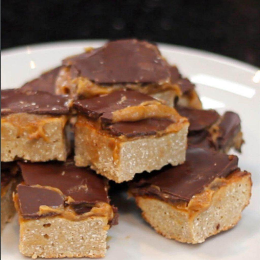 Healthy snack recipes: Protein millionaire's shortbread cut into squares and piled on a plate. 